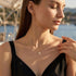 UNIQAL FARFALLA 14K GOLD Schmetterlingskette aus 14K-vergoldetem 925 Silber, am Model mit schwarzem Oberteil im warmen Sonnenlicht getragen.