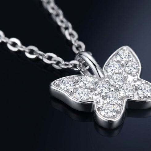 Nahaufnahme des FARFALLA Schmetterlingsanhängers von UNIQAL: zwölf Moissanite mit hellen Lichtreflexen auf dunklem Grund.