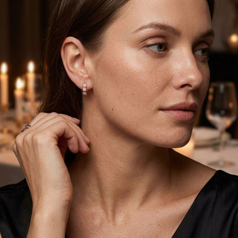UNIQAL FLORA SILBER ROSE Moissanit-Ohrringe zu einem schwarzen Outfit, getragen bei einem Dinner mit Kerzenschein im Hintergrund