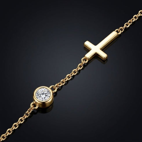 Makrodetail des UNIQAL GRACE 14K GOLD Moissanit-Armbands mit rundem Stein in Zargenfassung und poliertem Kreuzmotiv auf dunkler Oberfläche.