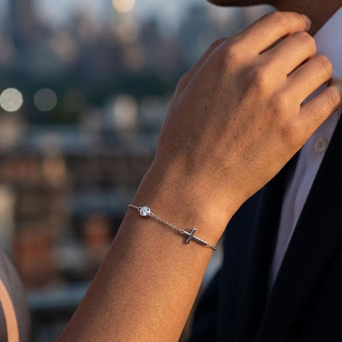 GRACE Moissanit-Armband von UNIQAL am angehobenen Handgelenk, kombiniert mit hellem Hemd und dunklem Blazer vor unscharfem Stadthintergrund.