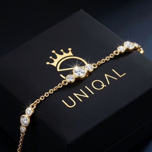 GRAZIA 14K GOLD Moissanit-Armband von UNIQAL diagonal auf einer schwarzen Markenbox, mit feinen Kettengliedern und goldenen Lichtreflexen.