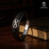 UNIQAL Infinity Armband aus schwarzem Leder mit silbernem Symbol der Unendlichkeit – elegant präsentiert auf einem Buch, Ausdruck von Wissen, Tiefe und Charakter.