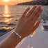 Infinity Schmuckarmband mit funkelnden Moissanit Steinen getragen im warmen Licht des Sonnenuntergangs am Meer