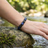 Lapis Lazuli Edelsteinarmband auf Felsen getragen mit strukturierten Platten und gravierbarem Makrameeverschluss