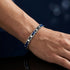 Elegantes Uniqal NAUTIS Armband aus Edelstahl und blauer Keramik mit Ankersymbolen und moderner Unisex-Optik am Handgelenk