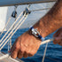 UNIQAL NAVIGATOR Sailing Bracelet am Handgelenk eines Seemanns während der Arbeit mit Tauwerk auf offenem Wasser