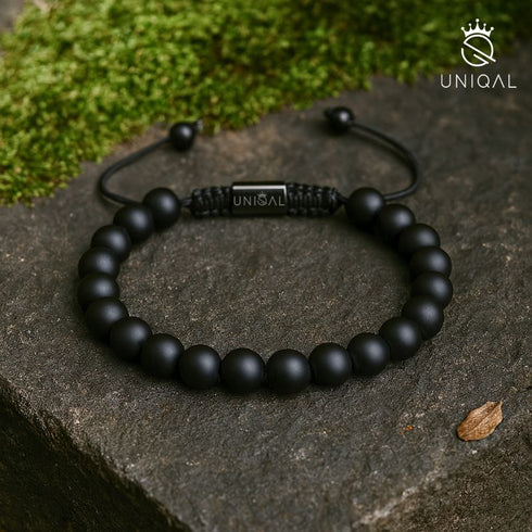 Armband aus mattem schwarzen Onyx auf Naturstein fotografiert – Symbol für Erdung, Stärke und Klarheit uniqal