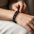 Uniqal PASSION LAVA SPECTROLITE Armband am Handgelenk – schwarze Lavasteine, graue Spectrolite-Perlen und schwarzes Flechtleder für einen modernen Casual-Look