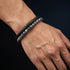 Uniqal PASSION SPECTROLITE Herrenarmband am Handgelenk – graue Spectrolite-Perlen kombiniert mit schwarzem Flechtleder für einen modernen Männerlook
