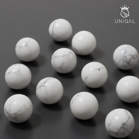 Uniqal Howlith Perlen einzeln angeordnet auf dunklem Untergrund