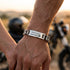 SILVER RIDER silbernes Armband am Handgelenk während einer Fahrt entlang einer Küstenstraße mit urbanem Lifestyle mit Gravur