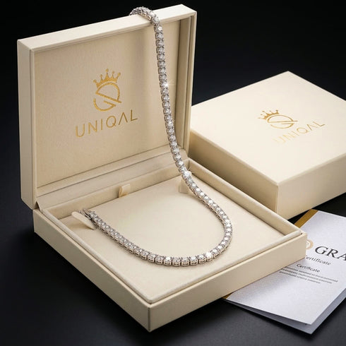UNIQAL Tenniskette Moissanit 2 mm in einer geöffneten cremefarbenen UNIQAL Geschenkbox, daneben ein GRA-Zertifikat.