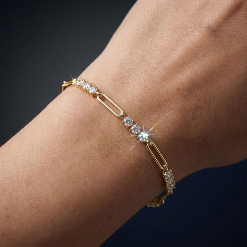 Nahaufnahme des TRIA LINK 14K GOLD Moissanit-Armbands von UNIQAL mit sichtbaren Steinfacetten zwischen glatten goldfarbenen Konturen.