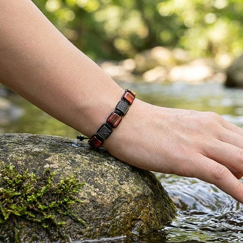 UNIQAL Unisex Armband mit rotem Tigerauge am Handgelenk getragen in natürlicher Outdoor-Umgebung
