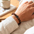 Uniqal Armband aus rotem Tigerauge mit schwarzem Kreuz am Handgelenk – moderner Look und ausgewogene Proportionen