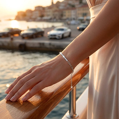VALERIA Moissanit Armband am Handgelenk vor maritimer Stadtkulisse getragen, filigraner Damenschmuck mit gravierbarem Herzdetail