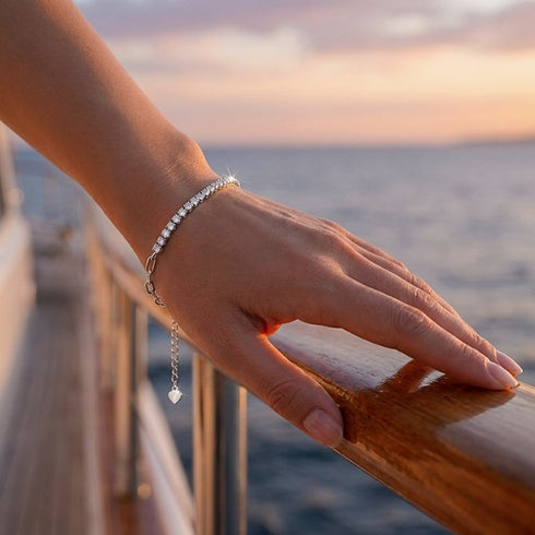 VALERIA Schmuckarmband mit Moissanit Steinen getragen bei Sonnenuntergang am Meer, elegantes Design mit personalisierbarem Anhänger