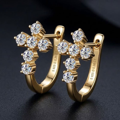 VERA 14K GOLD von UNIQAL als christlicher Ohrschmuck auf einer dunklen Oberfläche, mit warmem Goldton, glatten Bögen und farblosen Moissaniten.