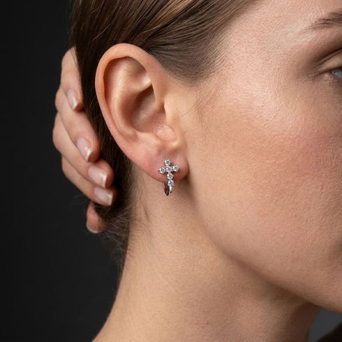 VERA von UNIQAL am Ohr, seitlich fotografiert: filigraner christlicher Ohrschmuck mit hellem Steinkreuz und einem glatten, gebogenen Unterteil.