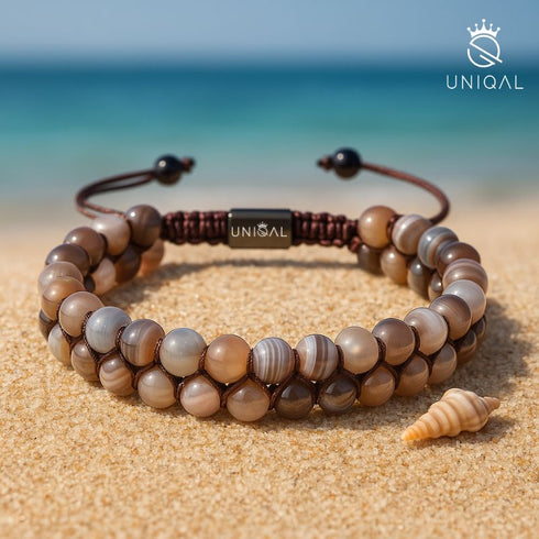 Zweireihiges Botswana-Achat-Armband aus echten Edelsteinperlen auf Sand – Symbol für Ruhe, Balance und Verbundenheit mit der Natur.